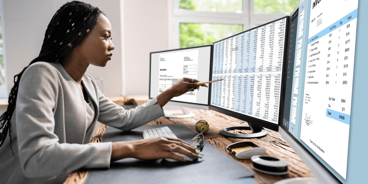 A woman analyzing invoices and financial spreadsheets across multiple monitors at her desk.