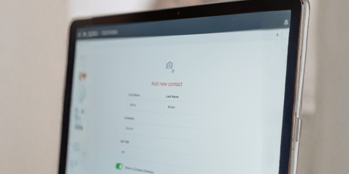 A laptop screen displaying an 'Add new contact' CRM form with fields for first name, last name, company, and job title.